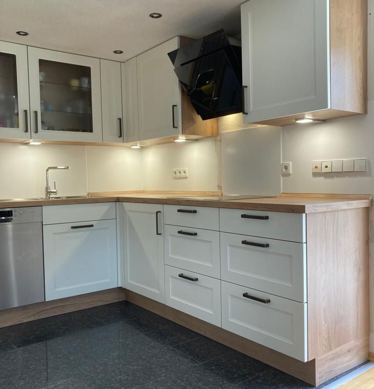 eine Küche mit weißen Schränken und Holzarbeitsplatten