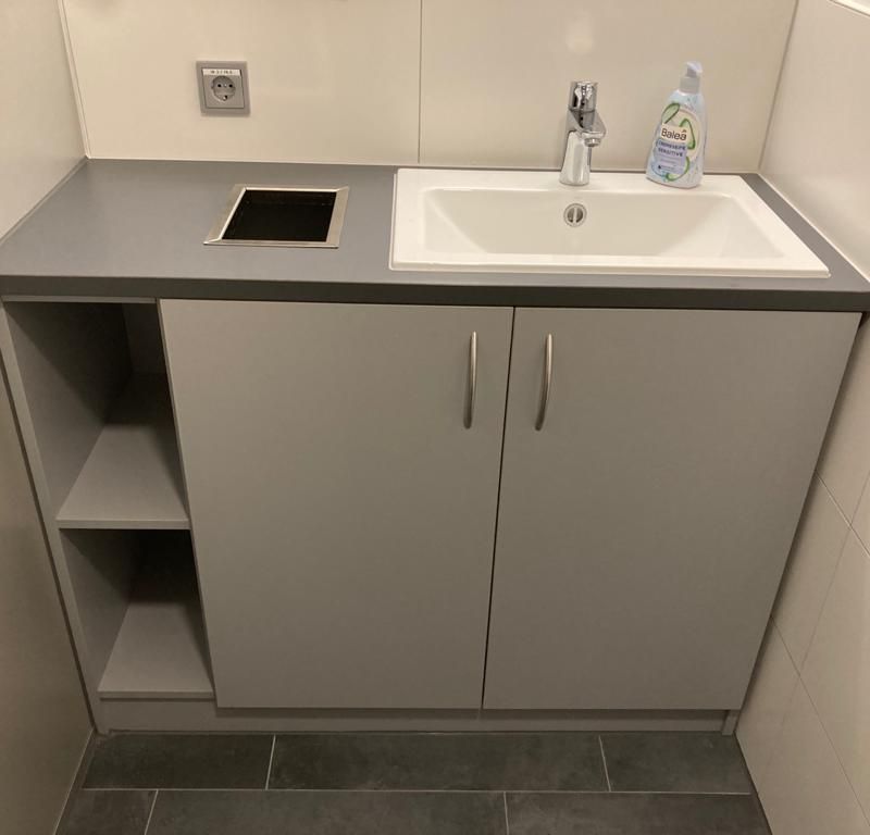 Eine kleine weiße Küchenzeile mit Spüle und Schranken