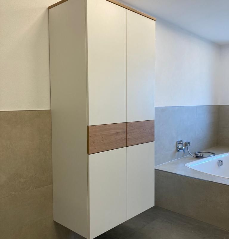 ein Badezimmer mit einem weißen Hängeschrank und einer Badewanne .