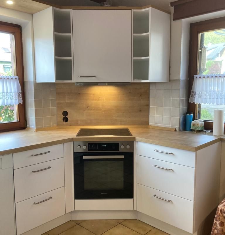 Eine weiße Küche mit einem Hern in der abgeschrägten Ecke