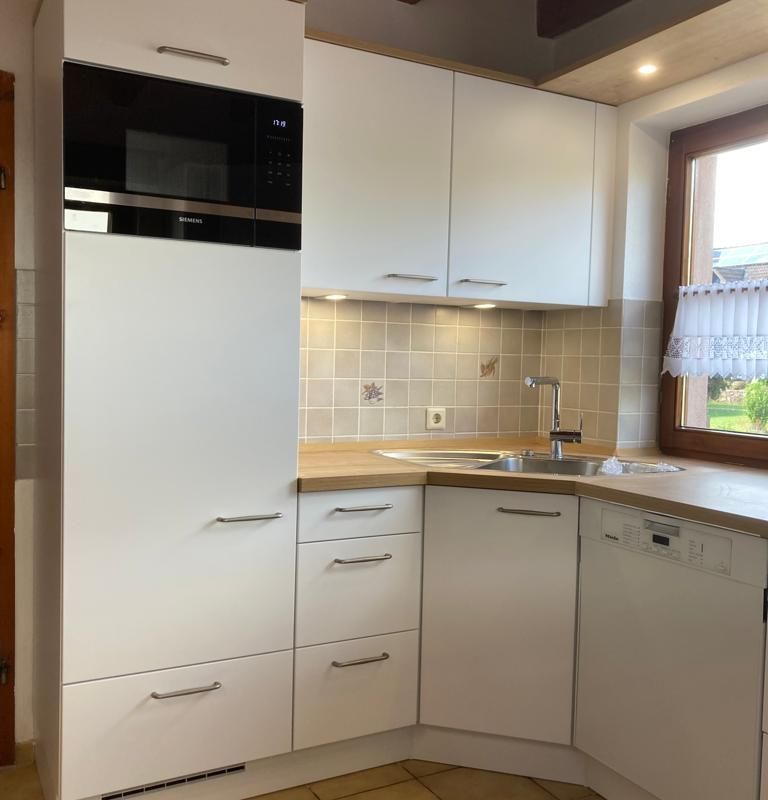 eine Küche mit weißen Schränken und einem Mikrowellenherd