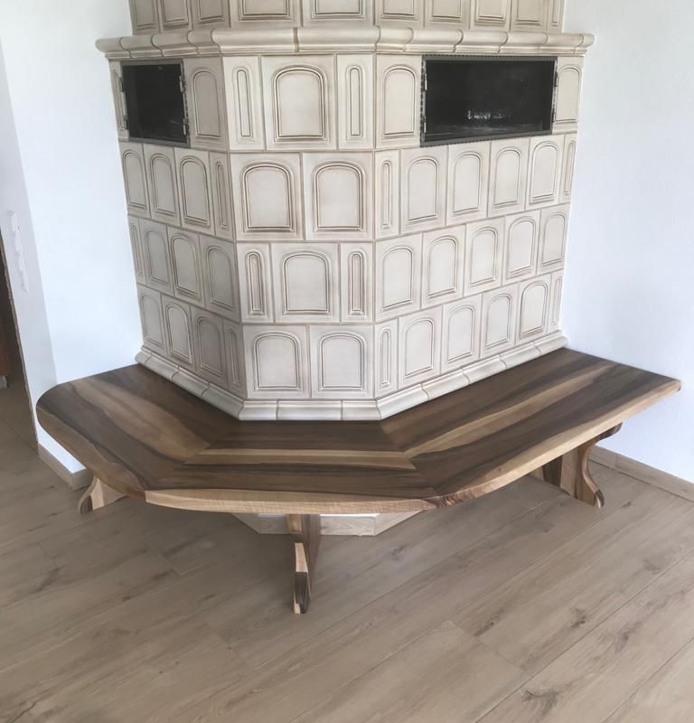 Eine Holzbank an einem Kachelofen