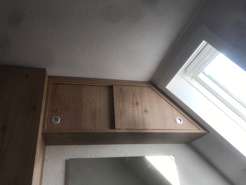 Ein brauner Hängeschrank an eine Wandschräge angepasst