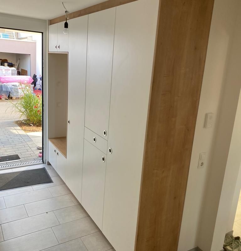 ein Flur mit weißen und braunen Schränken mit einer Einbuchtung zum Sitzen