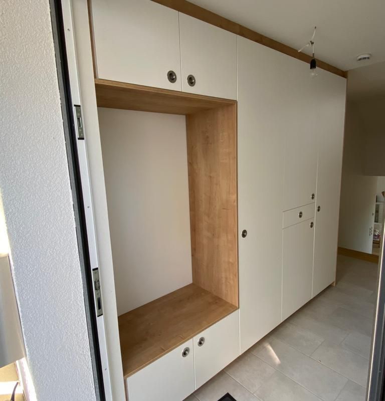 ein Flur mit weißen und braunen Schränken mit einer Einbuchtung zum Sitzen