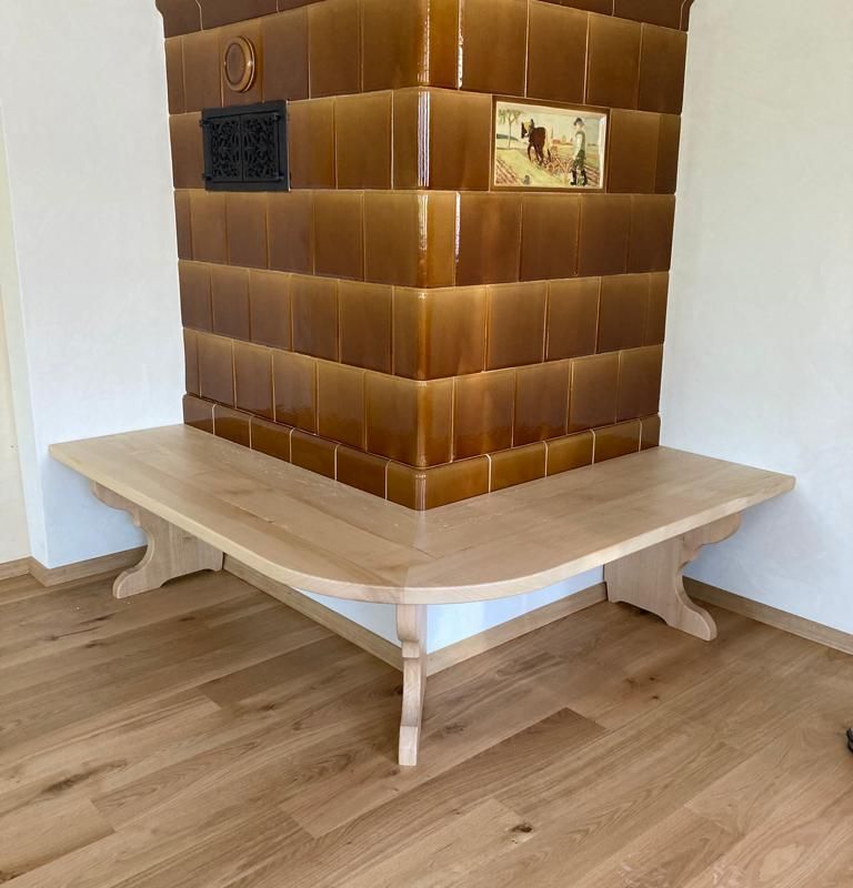 Eine Holzbank an einem Kachelofen