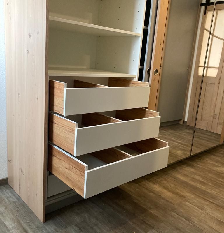 ein Schrank mit drei Schubladen und einem Spiegel .