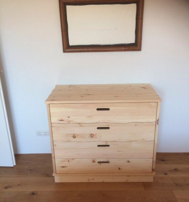 eine Holzkommode mit drei Schubladen und einem Spiegel an der Wand