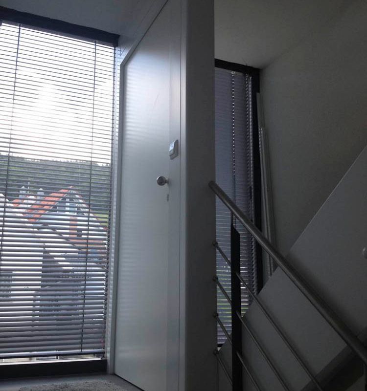 eine Treppe mit Holzstufen und einem Holzgeländer und einer Tür auf dem Treppenabsatz