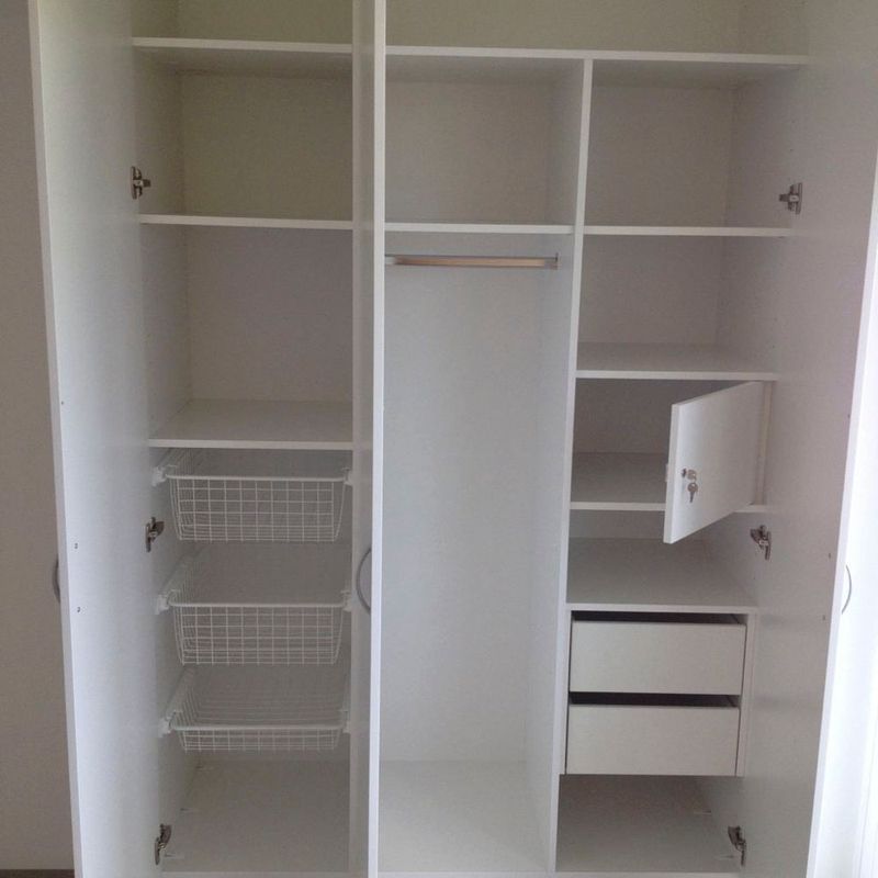 ein weißer Schrank mit offener Tür und vielen Regalen und Schubladen