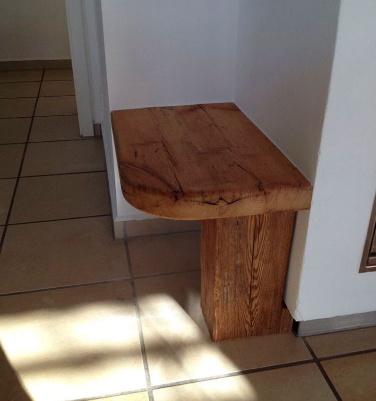 ein kleiner Holztisch steht auf einem Fliesenboden neben einer weißen Wand