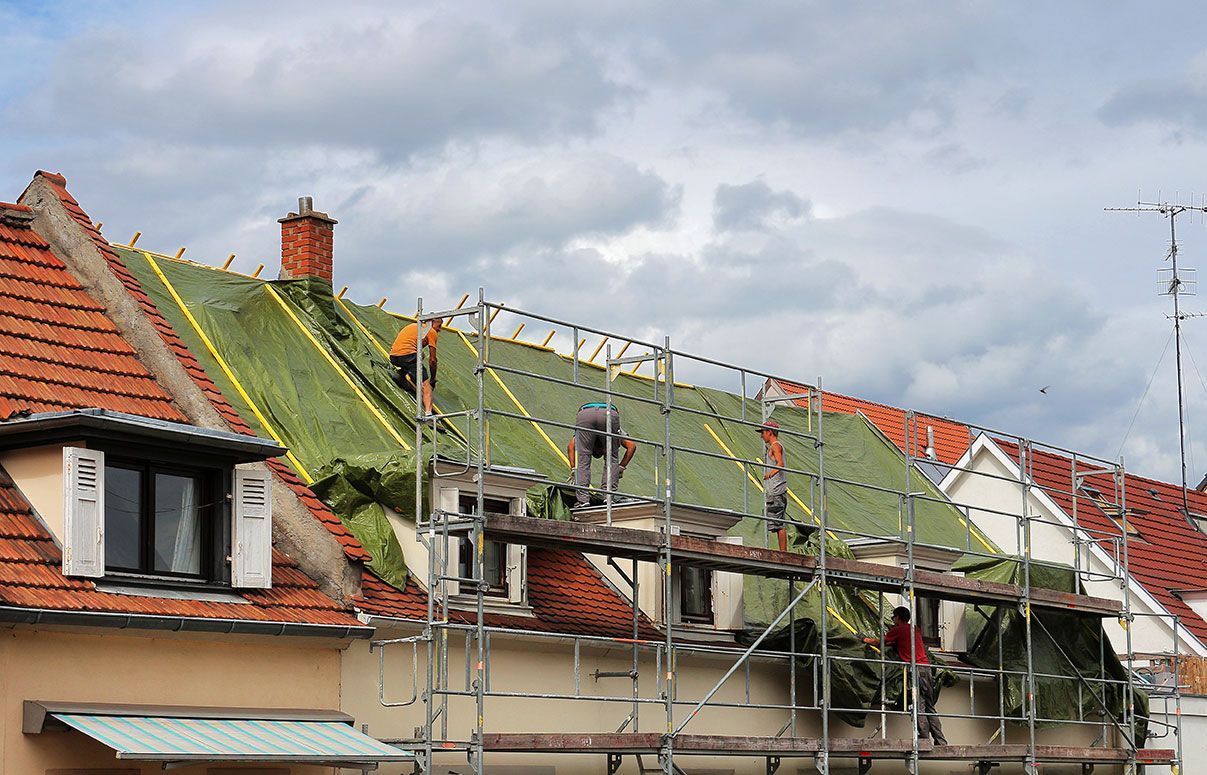 Bâche de protection verte qui recouvre une toiture endommagées