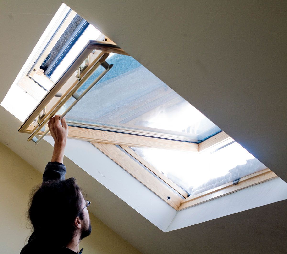 Homme qui ouvre une fenêtre de toit en bois