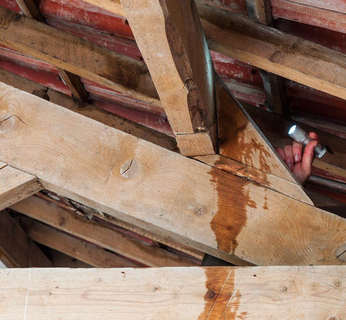 Homme qui recherche la fuite d'une toiture avec une lampe torche