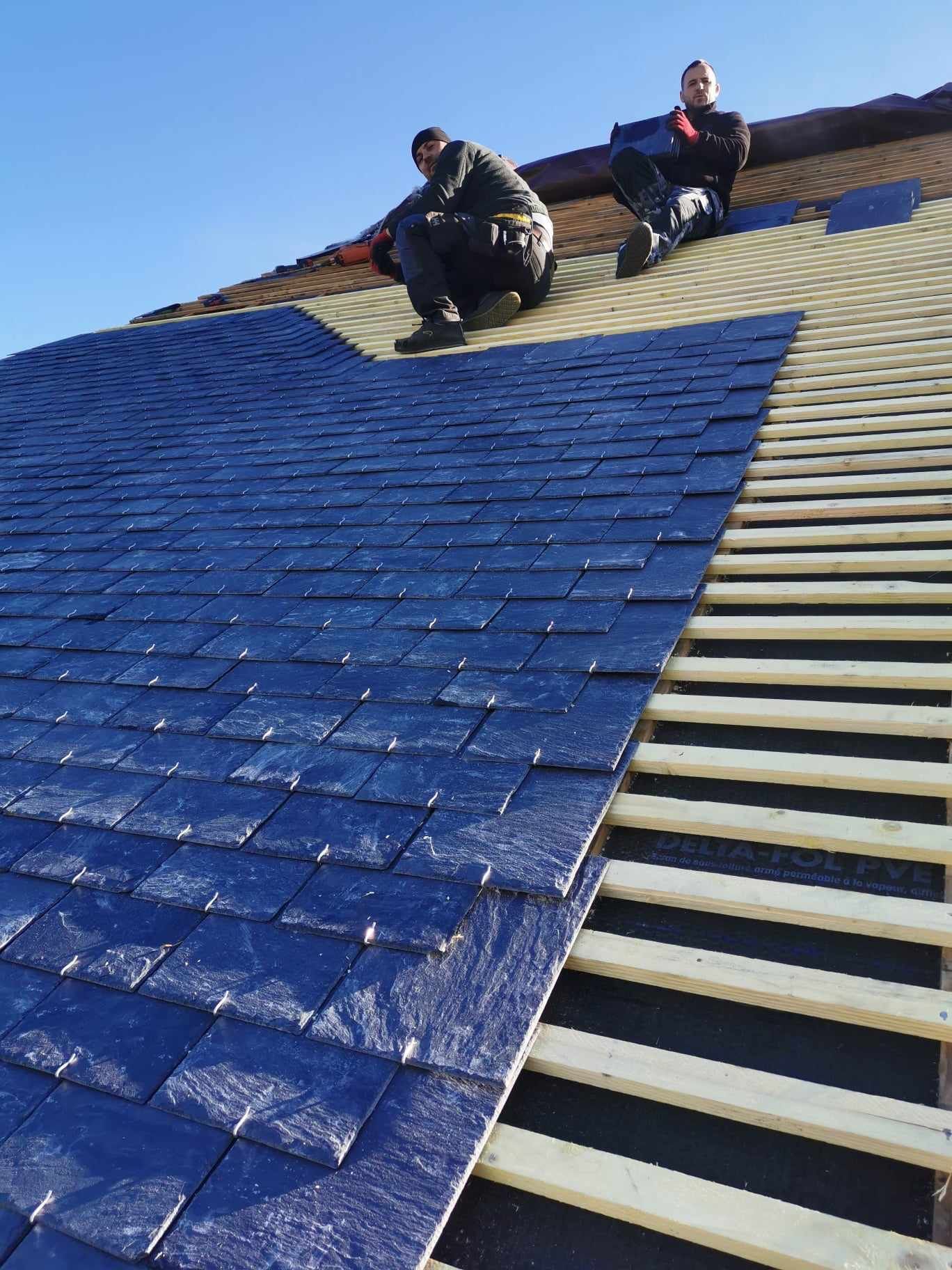 Deux ouvriers qui installent une couverture en ardoise