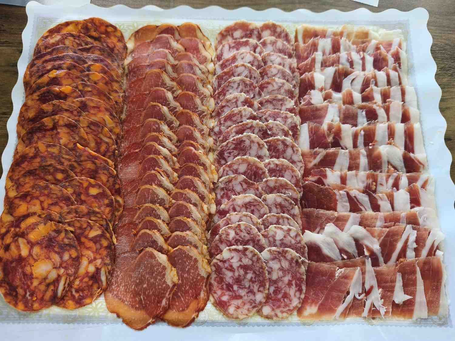 Disposición de embutidos loncheados en bandeja: chorizo, lonza, salami y jamón.