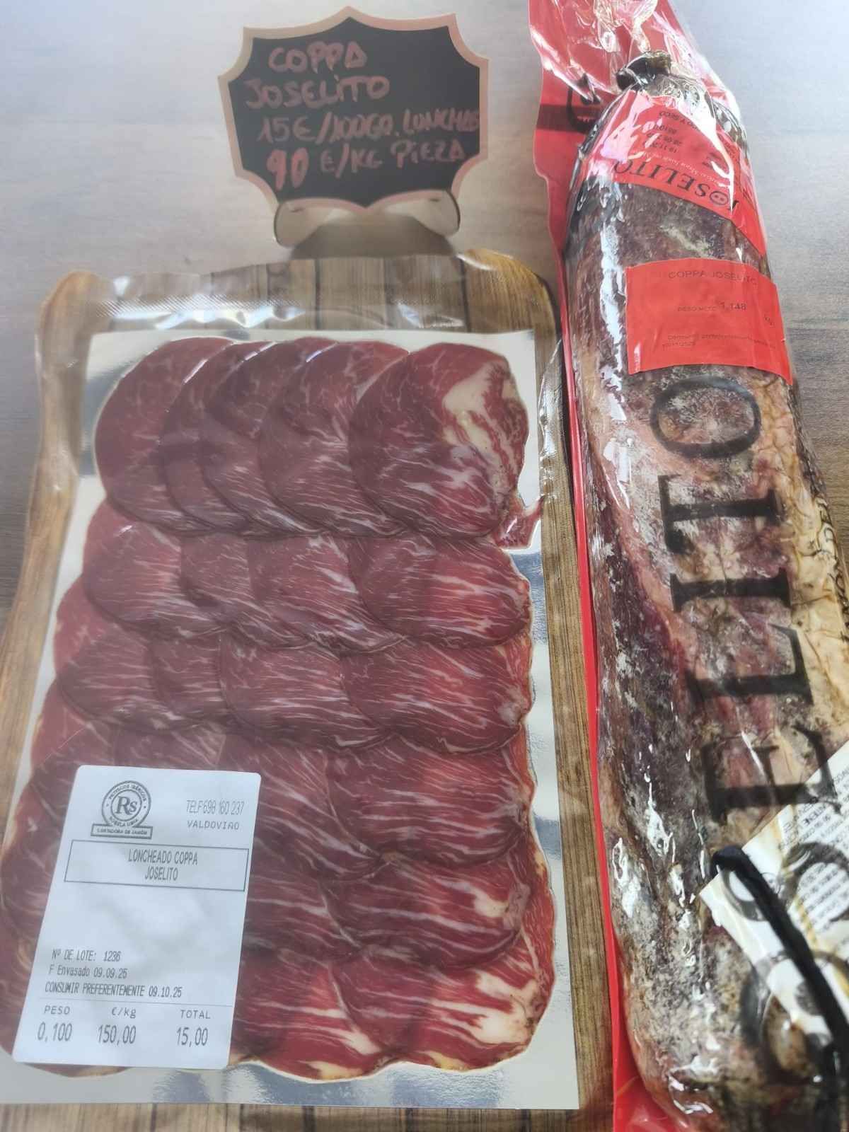 Coppa en lonchas previamente envasada y un embutido curado entero y envuelto sobre una superficie de madera.