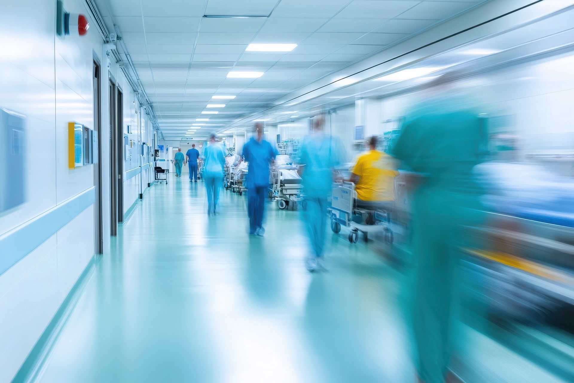 Couloir d'hôpital avec silhouettes floues de personnel médical et de patients.