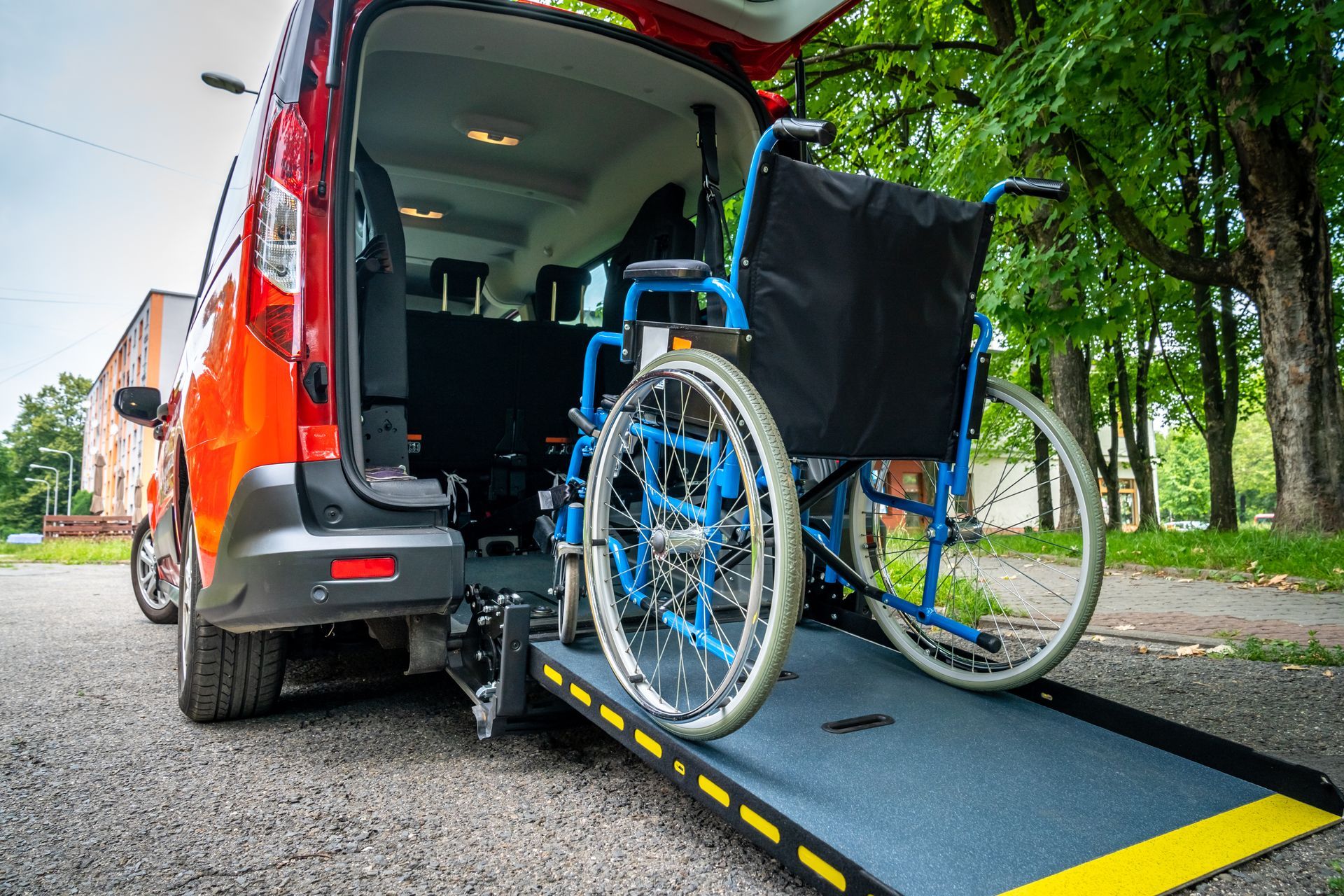 Un fauteuil roulant bleu sur une rampe pour monter dans un véhicule TPMR