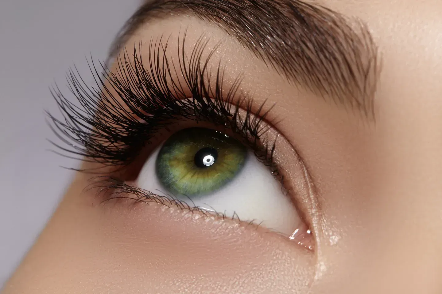 Un primer plano del ojo verde de una mujer con una lágrima saliendo de él.
