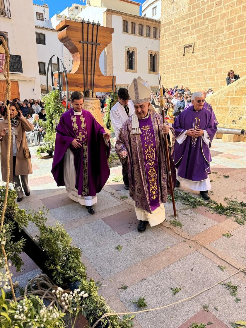 Durante una ceremonia religiosa, clérigos ataviados con ornamentos púrpuras desfilan por el patio soleado de una iglesia.