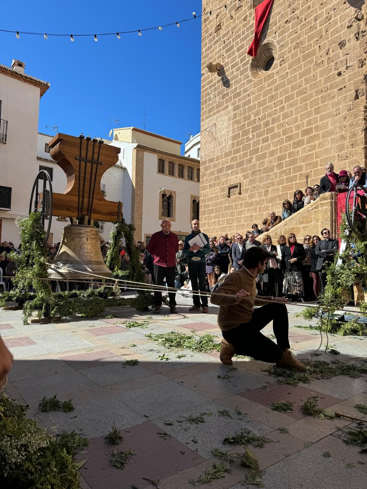 Una multitud se congregó en un patio soleado alrededor de una fuente de piedra, con una persona agachada en primer plano.
