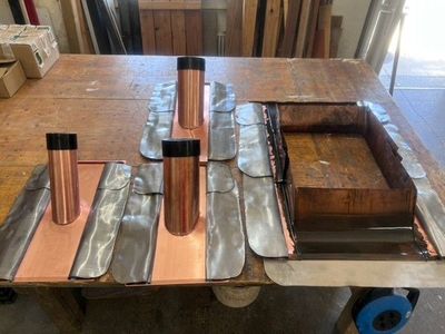 Kellerdecke mit roten und schwarzen Industrierohren und einer metallenen Steuereinheit an einer Betonwand