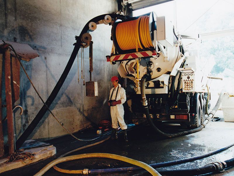 Ein Mann steht vor einem Lastwagen und arbeiten an einem Schacht auf der Straße.