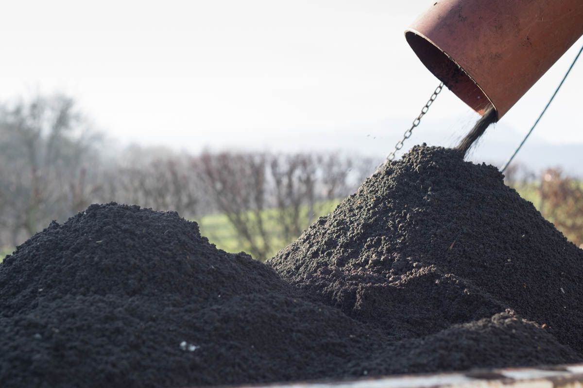 Ein großer Haufen schwarzer Erde wird aus einem Rohr gegossen