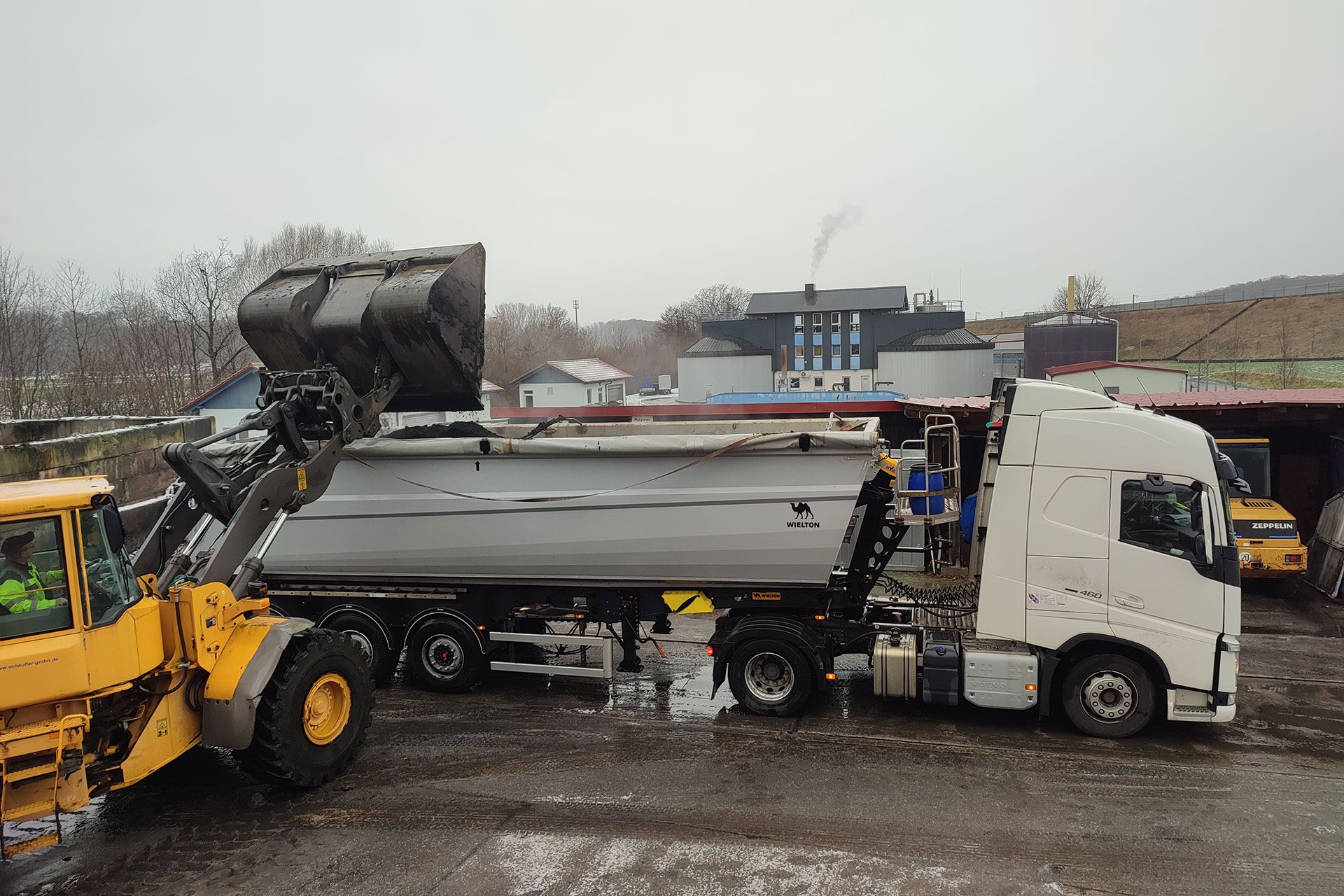 Ein gelber Lastwagen transportiert und entsorgt abgesaugten Materialien.