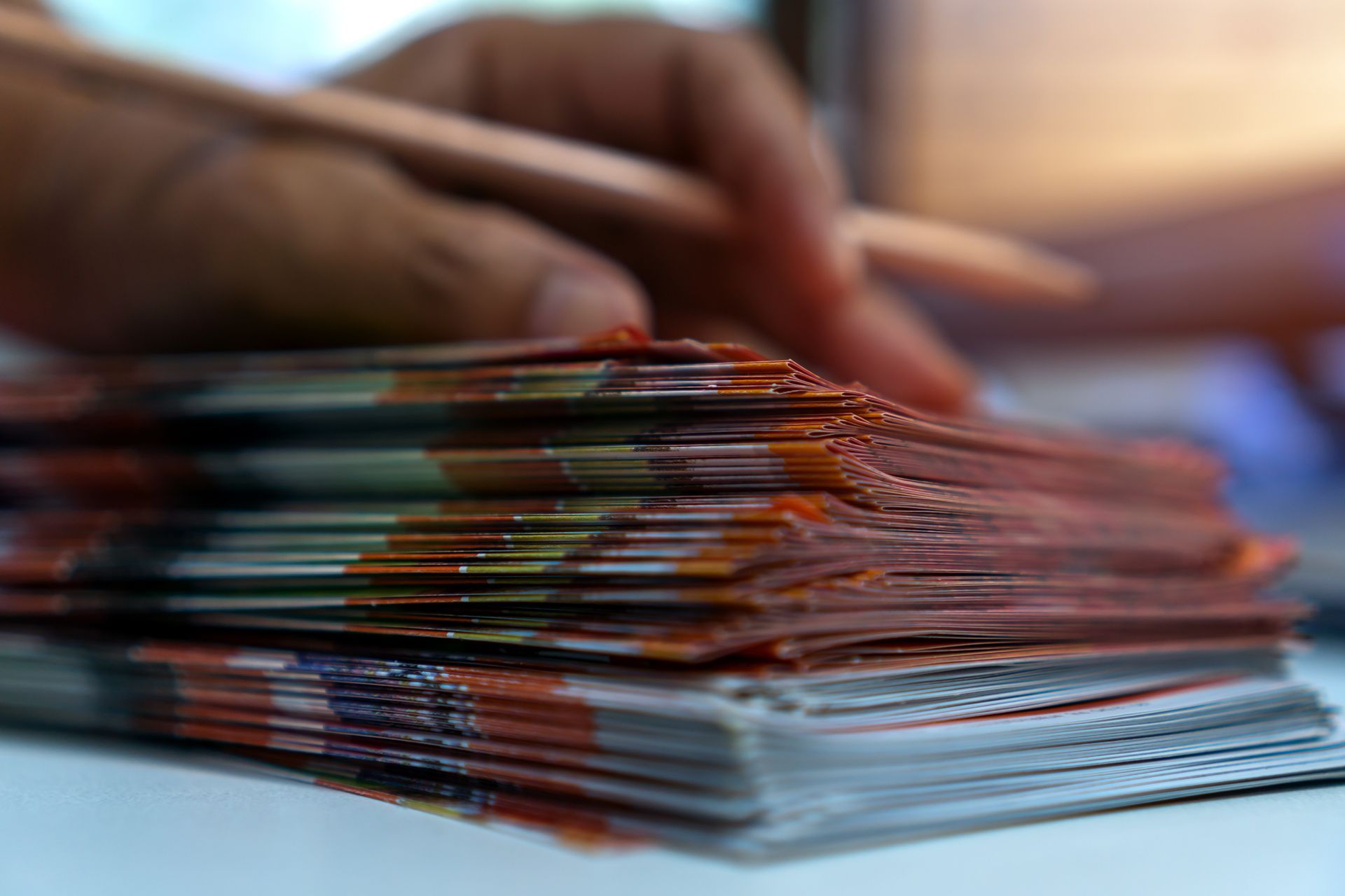 Gros plan sur une pile de feuilles de papier, une main tenant un crayon au-dessus des feuilles.