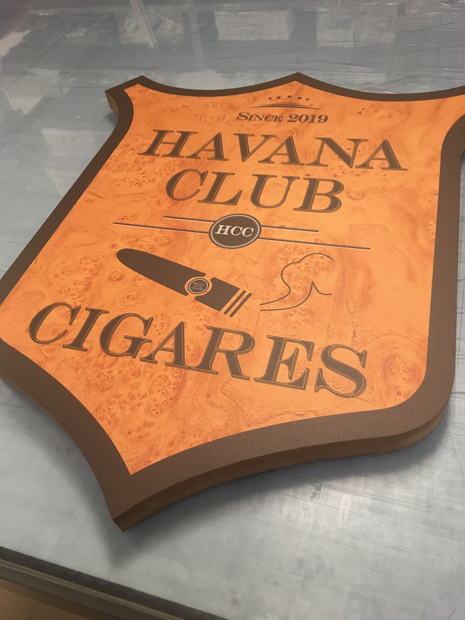 Panneau en forme de bouclier pour les cigares Havana Club, de couleur orange et marron, orné d'une illustration de cigare.