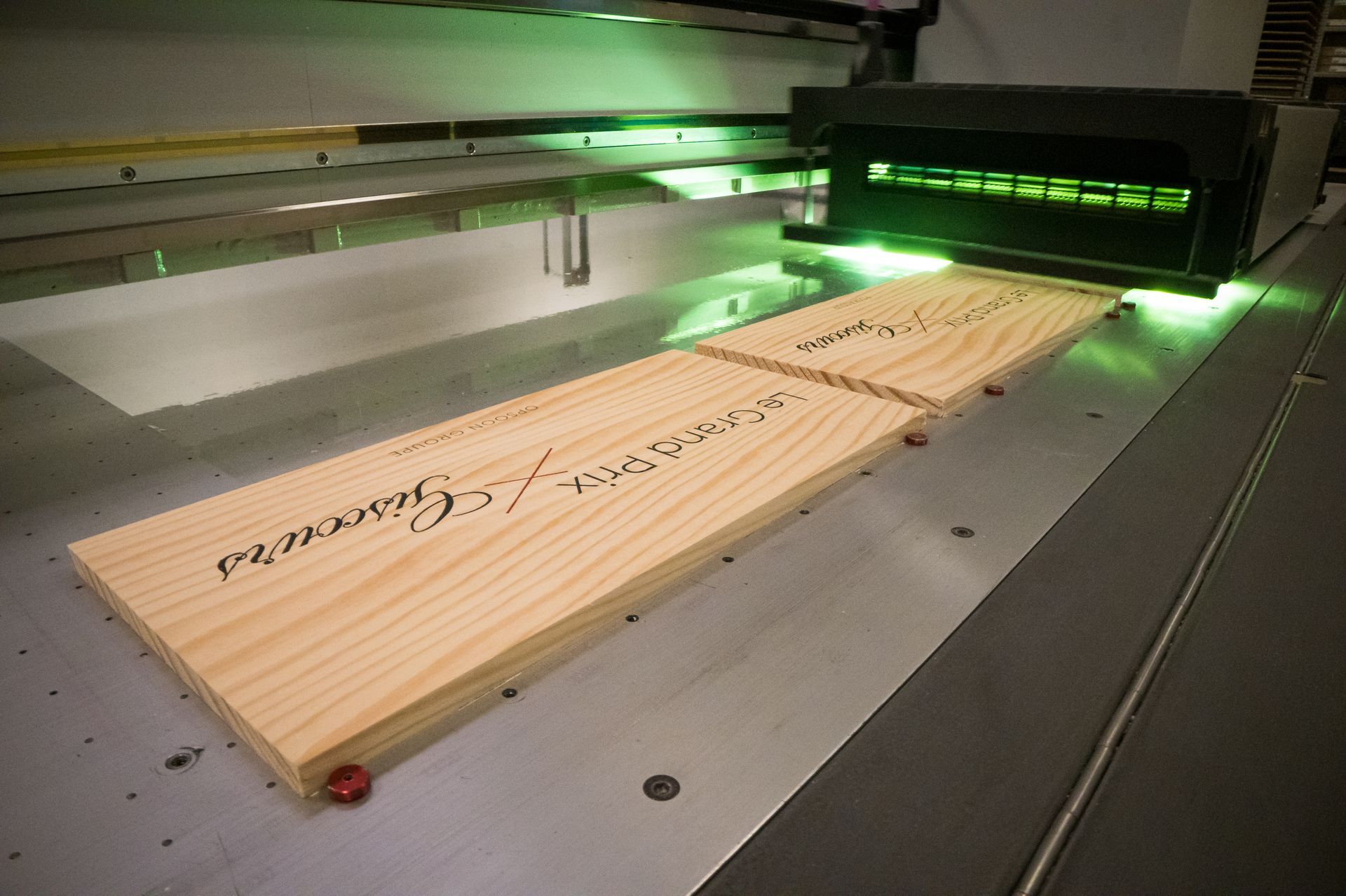 Des planches avec du texte imprimé sont éclairées par une lumière verte dans un environnement industriel.