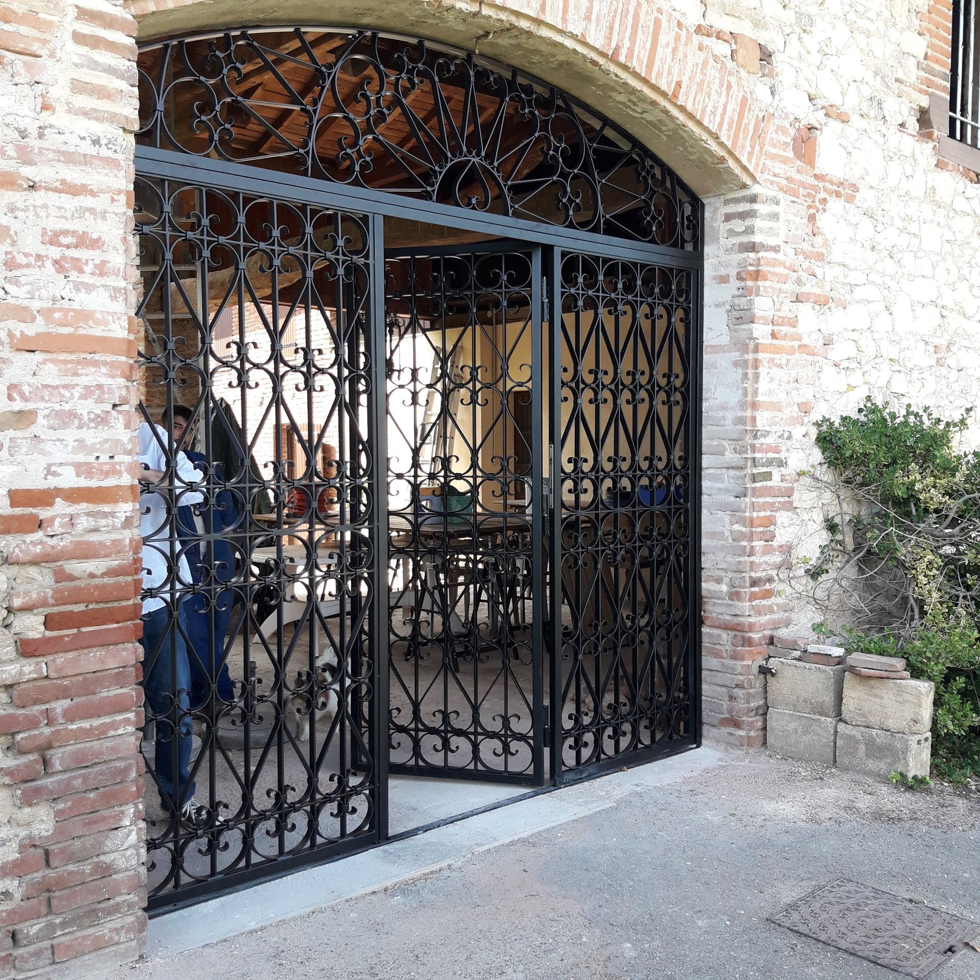 Portail en métal noir à l'entrée d'un bâtiment en briques.