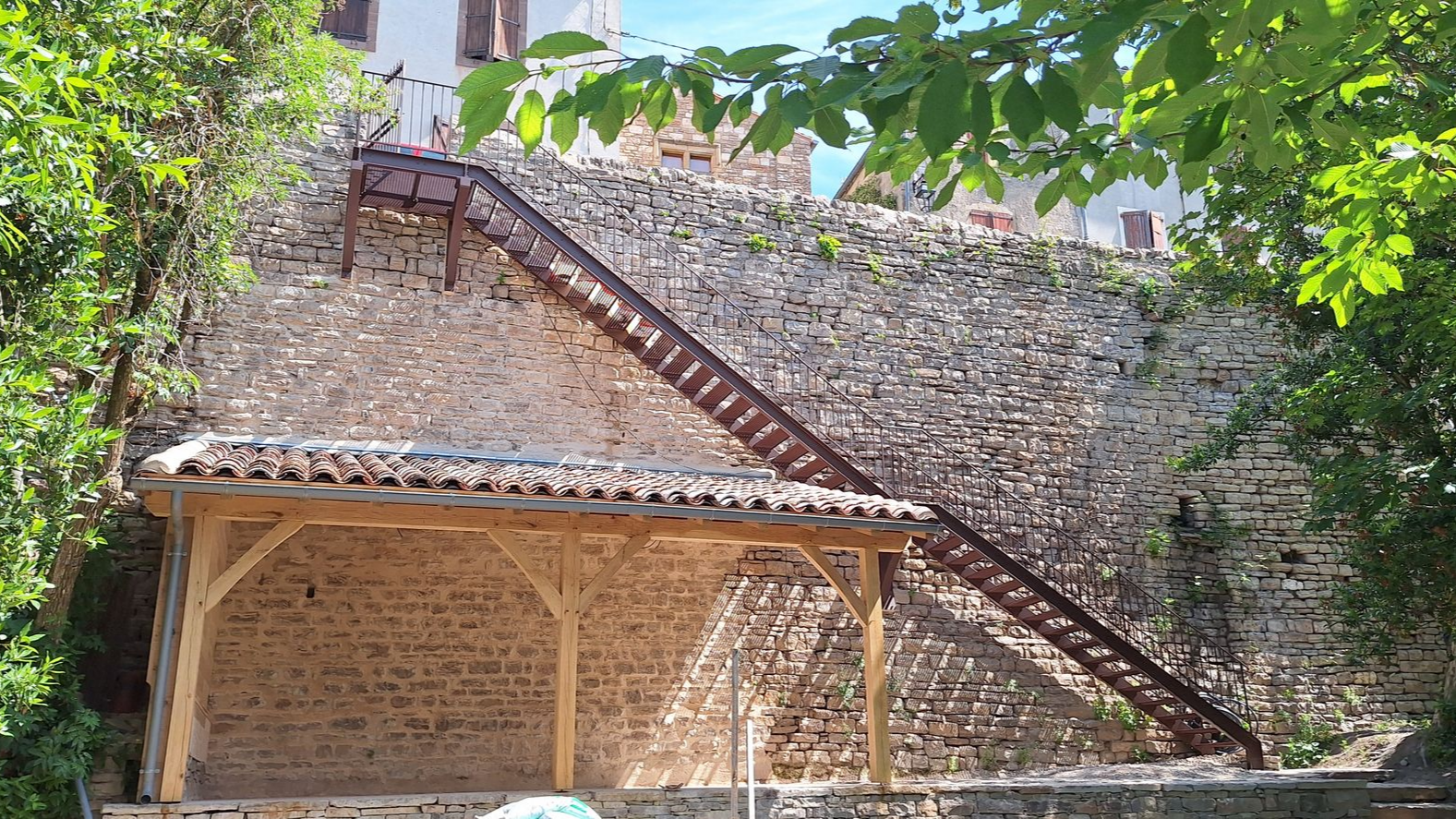 Un long escalier rouillé mène le long d'un mur de pierre.