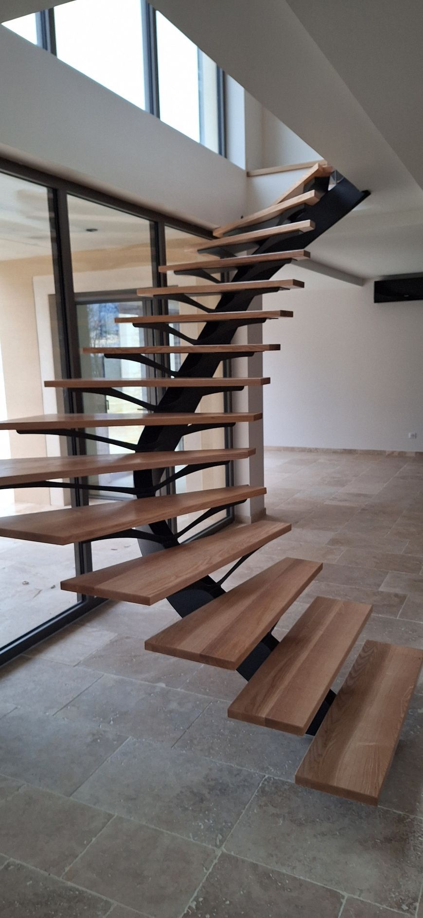 Un escalier moderne avec des marches en bois et un support en métal noir.