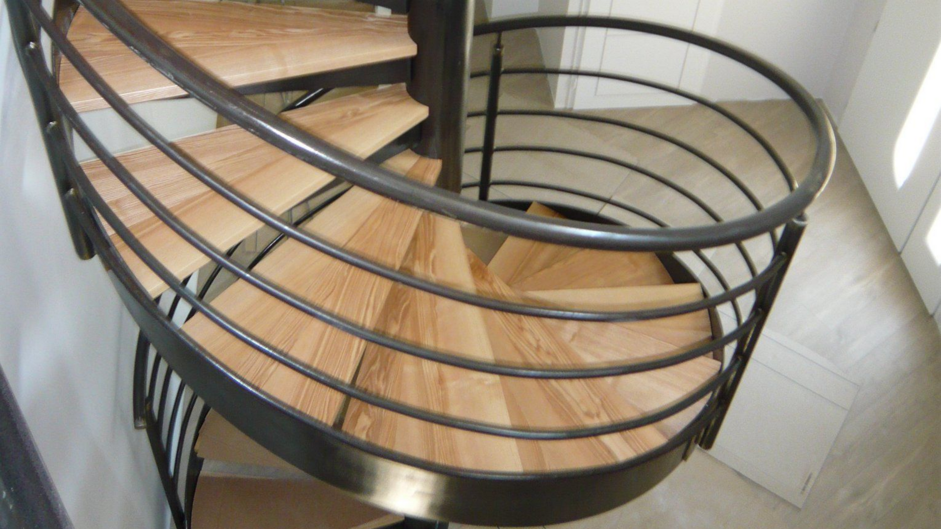 Un escalier coidale en bois et en fer dans une maison.