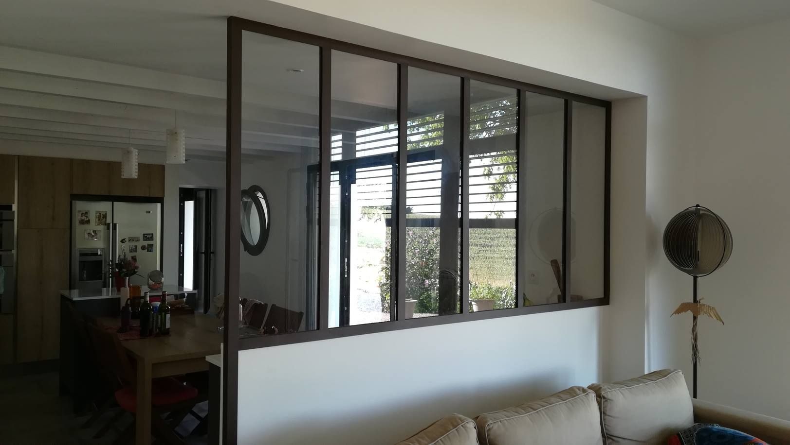 Intérieur avec panneaux muraux en verre, cadres bruns, séparant le salon de la salle à manger.