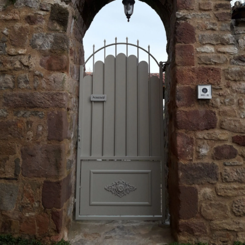 Portail gris enchâssé dans une arche en pierre.