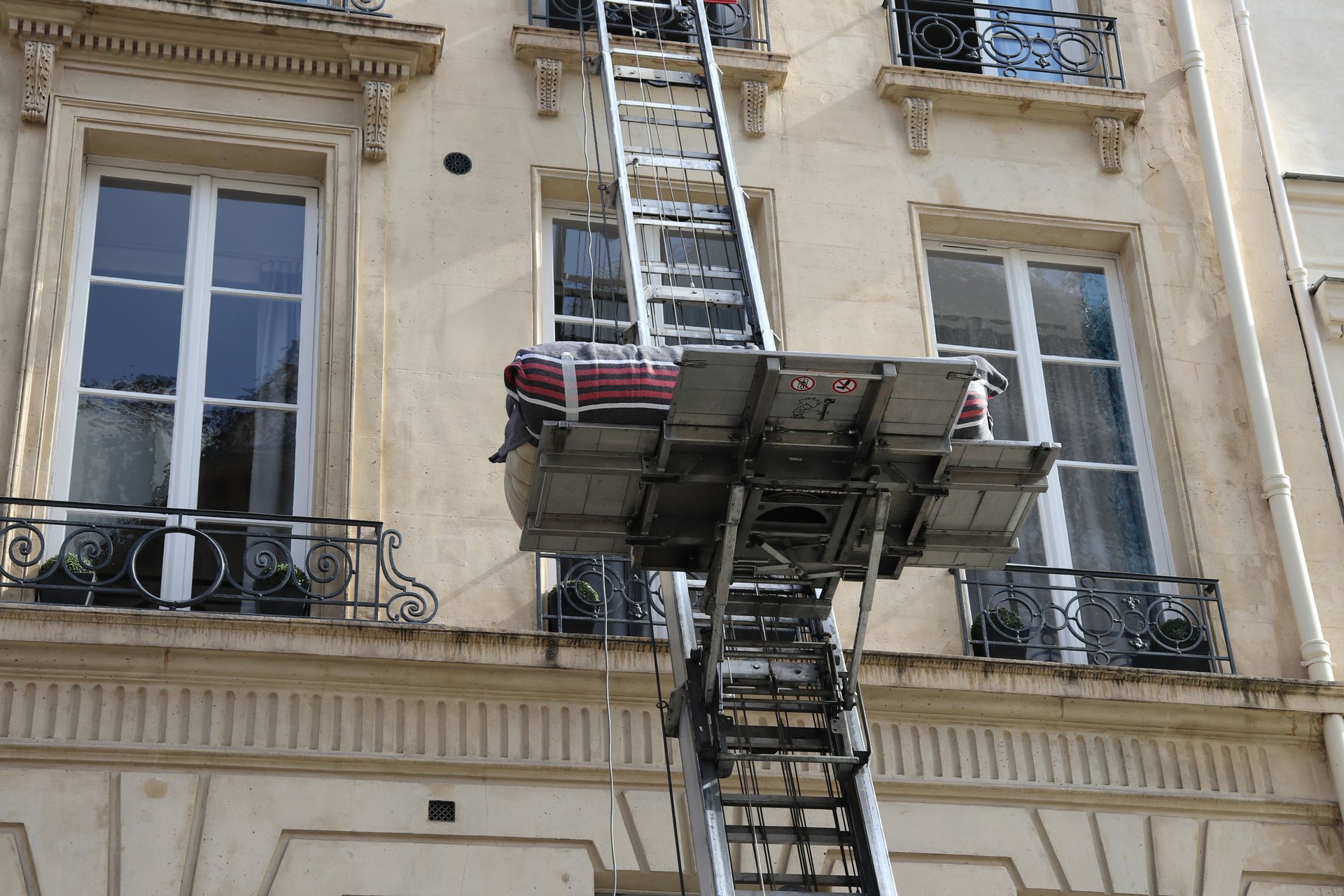 L'échelle d'un camion de pompiers était déployée jusqu'à un immeuble d'appartements en pierre avec balcons et fenêtres.