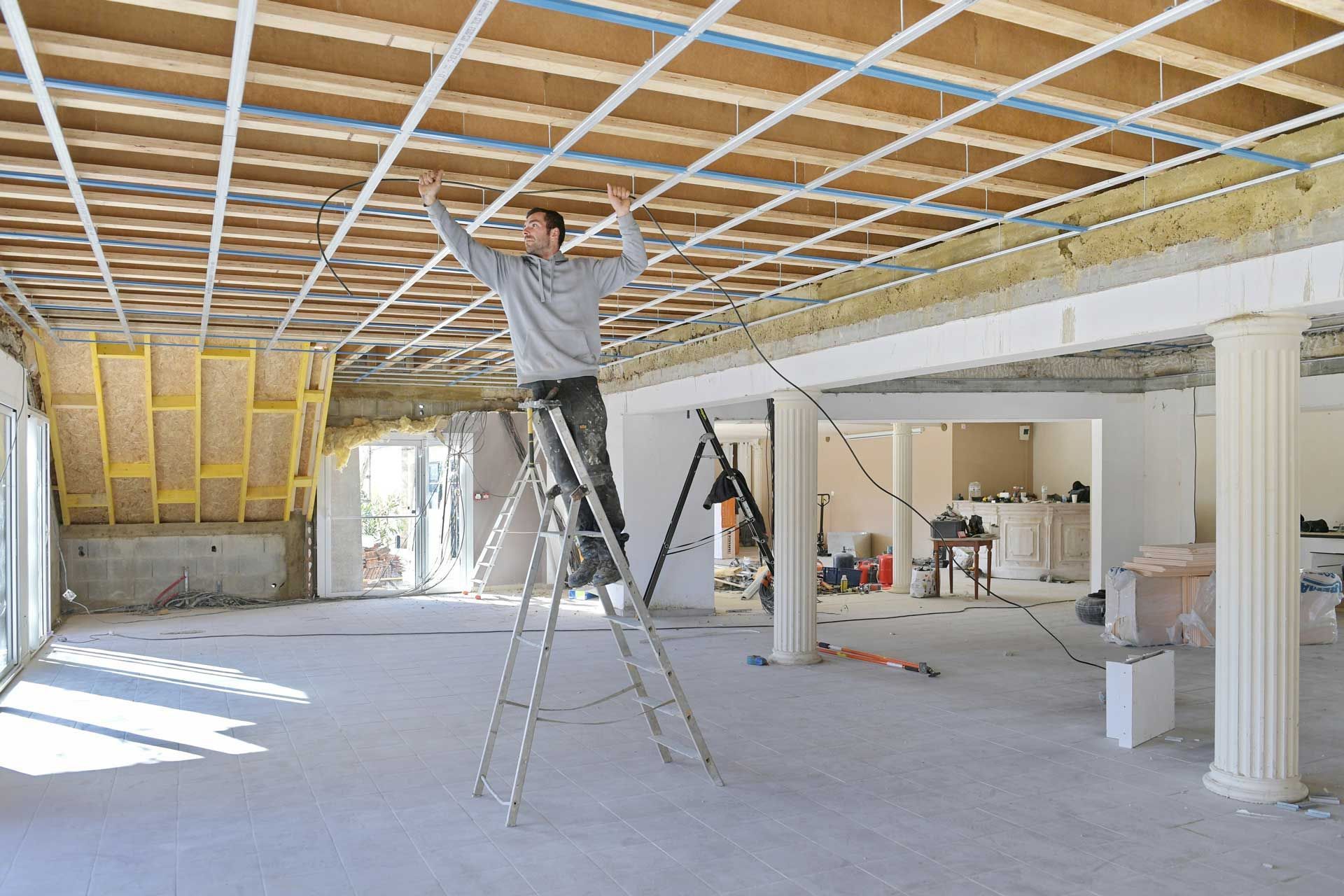 Un technicien de chez DN Rénovation installant des câbles dans une bâtisse en rénovation