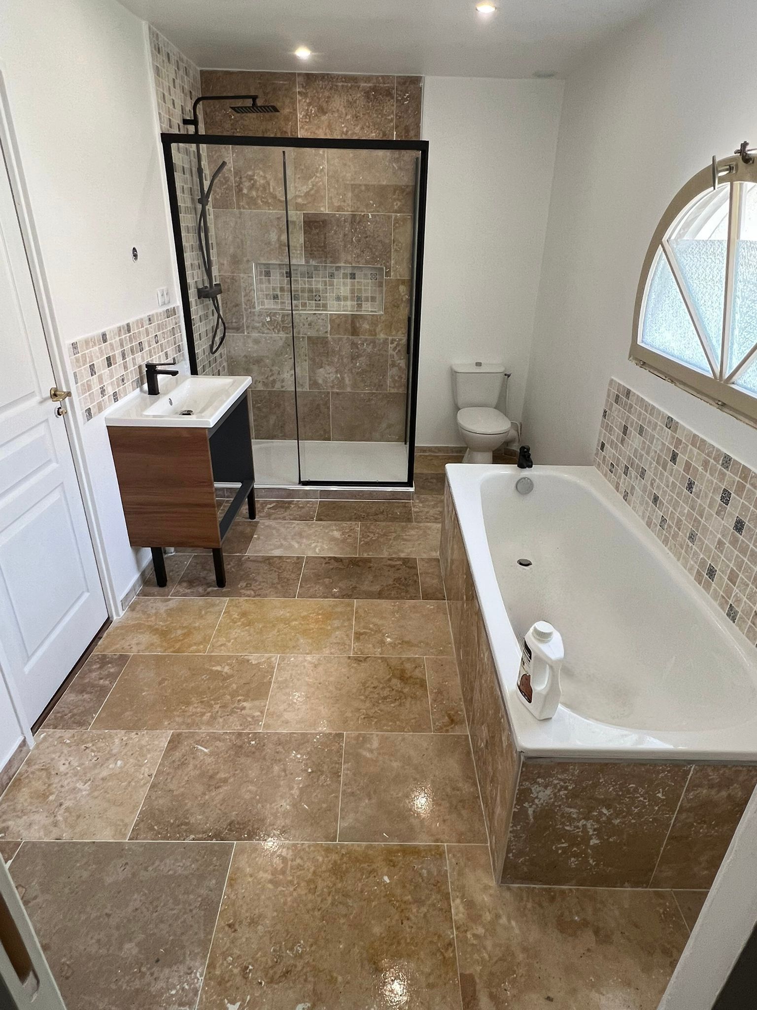 Salle de bains moderne avec baignoire, douche en verre, meuble-lavabo et sol carrelé