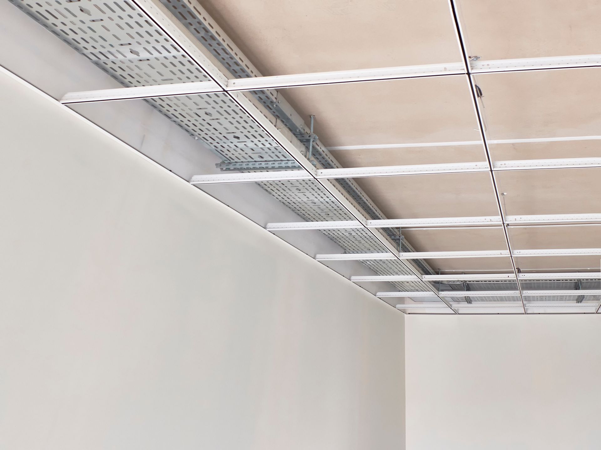 Plafond vide avec grille métallique apparente et mur blanc en construction