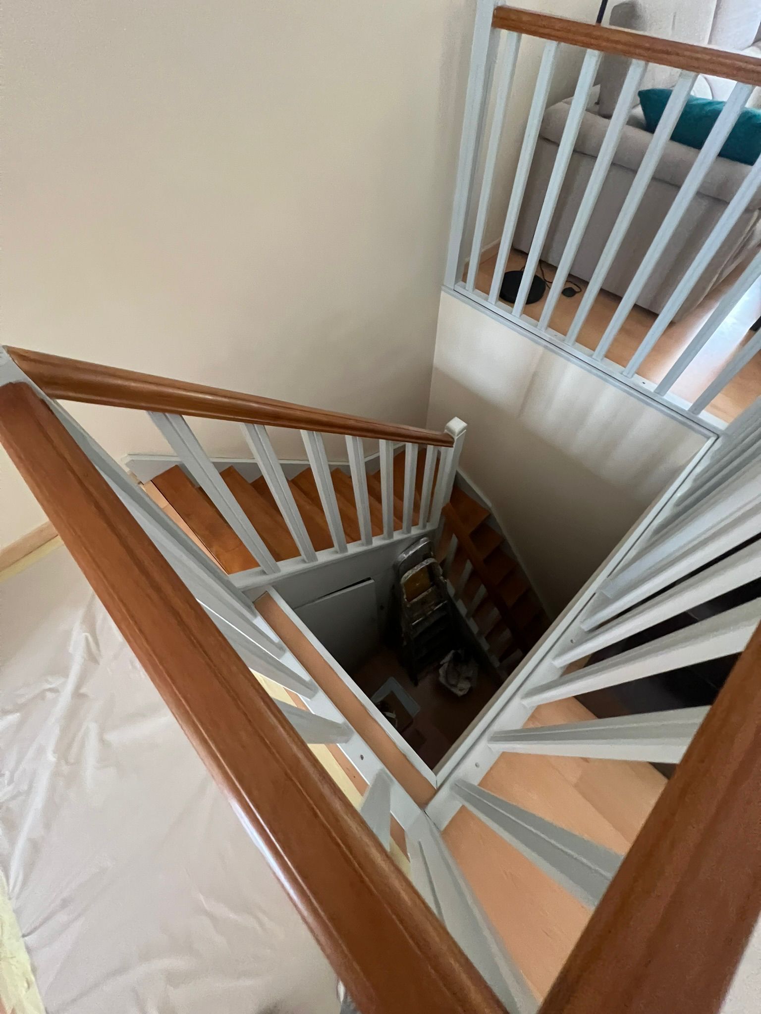 Vue d'en haut de la cage d'escalier avec ses rampes en bois et ses balustres blancs, donnant sur plusieurs étages.