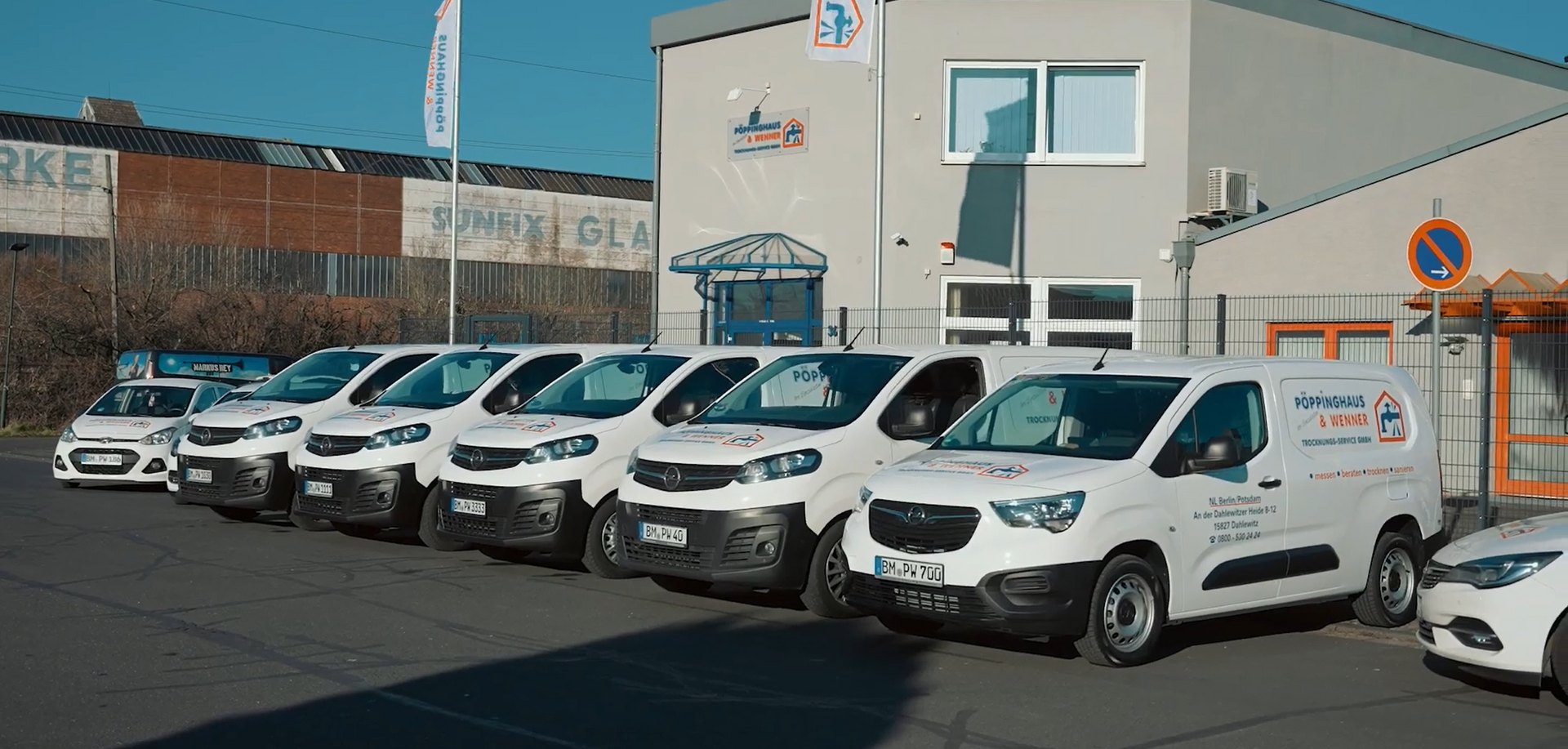 Ein Mann mit einer Schürze, auf der ein Haus steht, steht vor einem weißen Lieferwagen