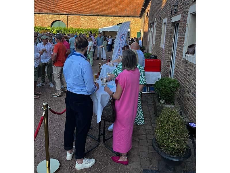 Eine Gruppe von Leuten steht vor einem Gebäude um einen Tisch herum.