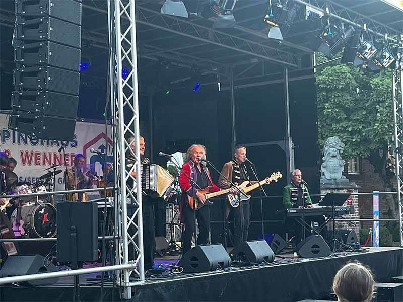 Eine Gruppe von Leuten spielt auf einer Bühne Instrumente.