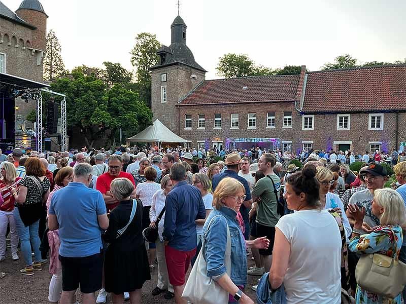 Eine große Gruppe von Menschen steht vor einem Schloss.