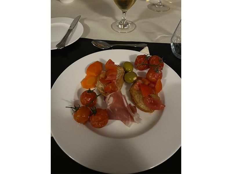 Ein Teller mit Essen auf einem Tisch mit einem Glas Wein im Hintergrund