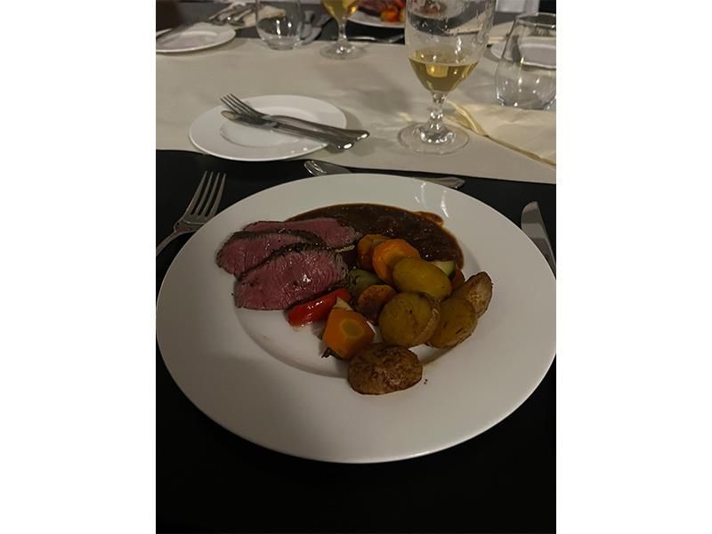 Ein weißer Teller mit Fleisch und Gemüse auf einem Tisch.